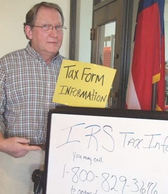 Library Manager Michael Humphrey points to sign informing the public about tax form issues